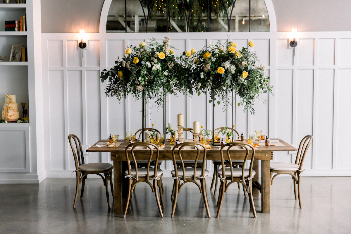 table arranged with green and yellow floral arrangment hanging above