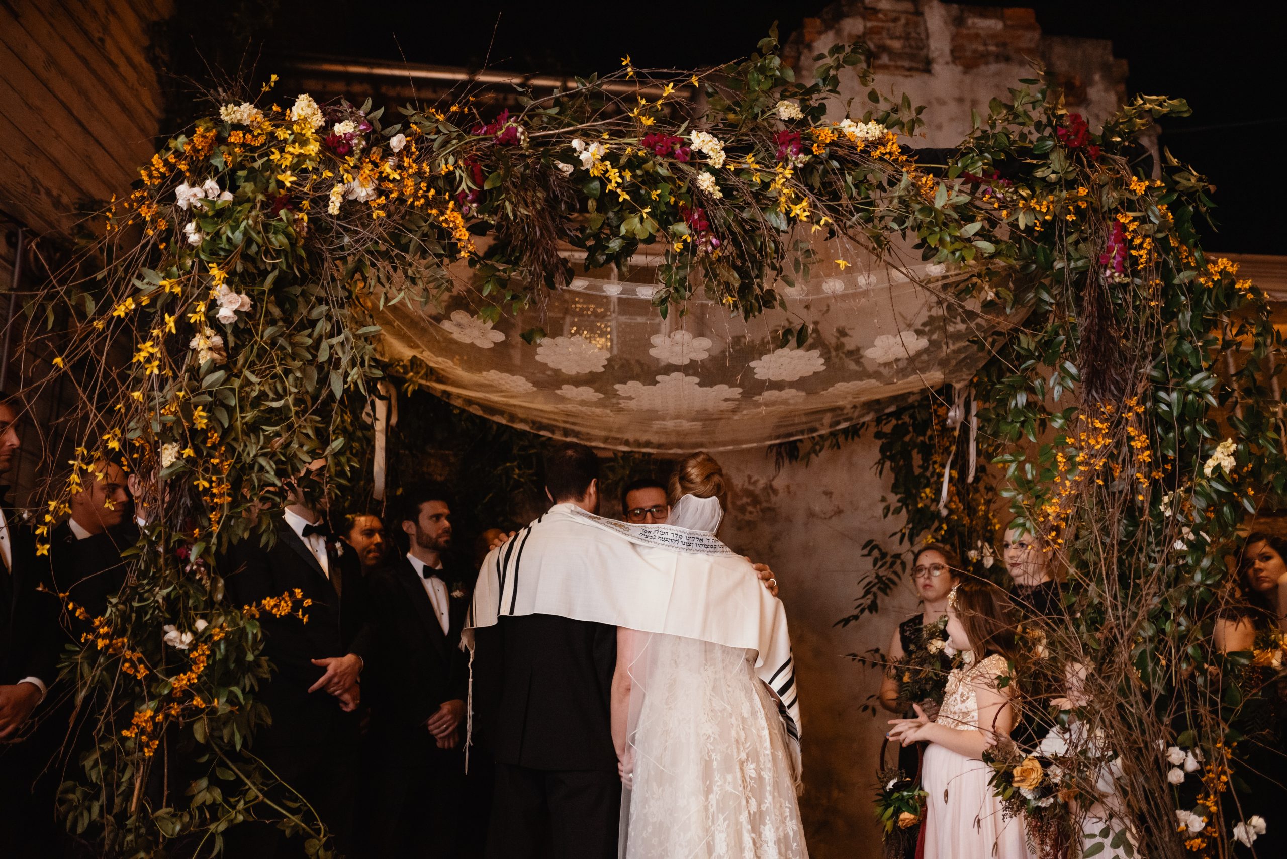 couple with shawl covering them at outdoor garden style ceremony 