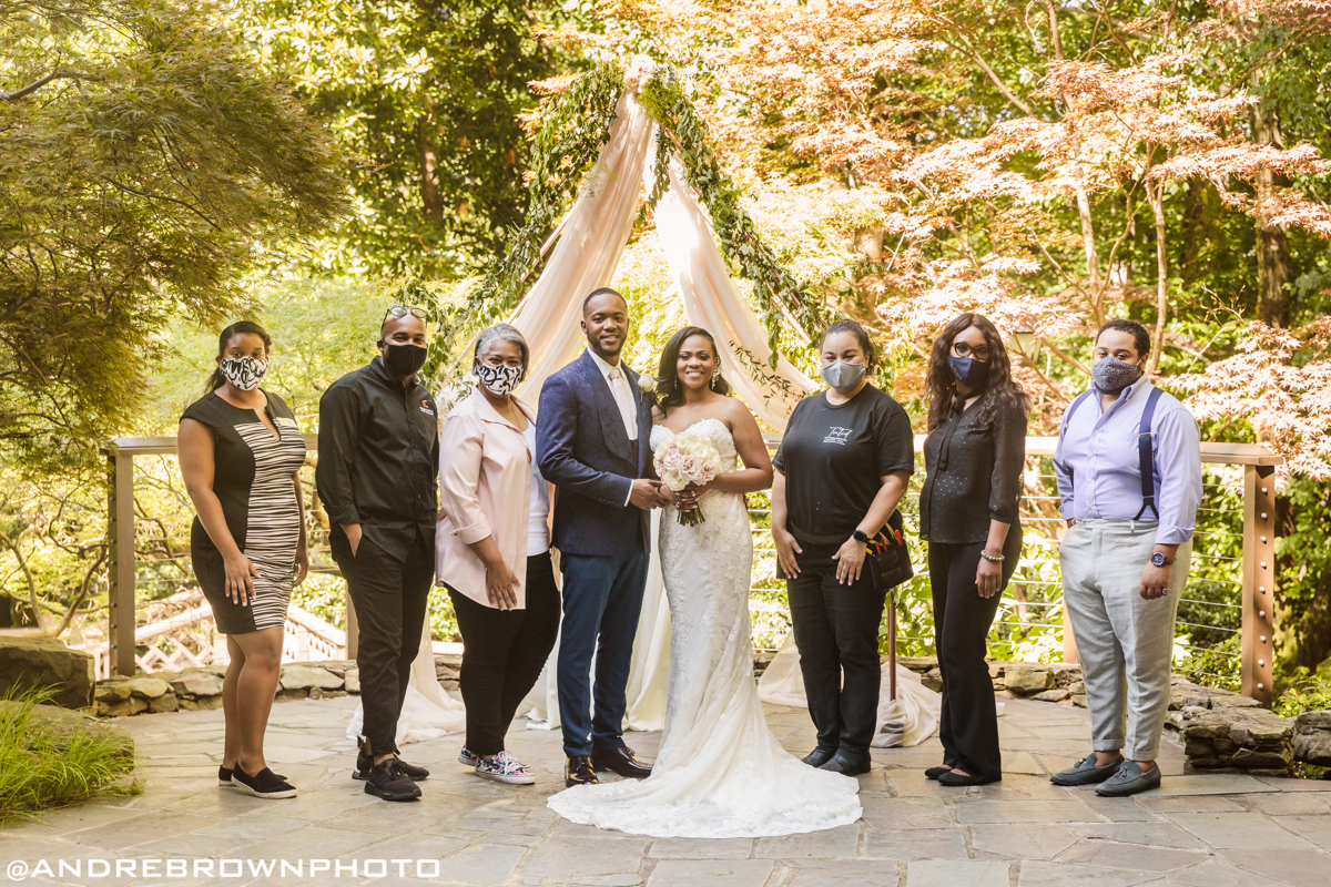 couple on wedding day surrounded by wedding planning team who are wearing masks