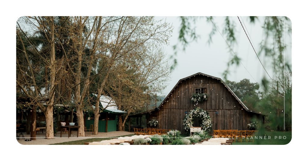 A rustic barn wedding venue featuring an outdoor ceremony setup with wooden chairs, lush greenery, white floral arrangements, and a decorative wedding arch, showcasing thoughtful wedding planning and event design.